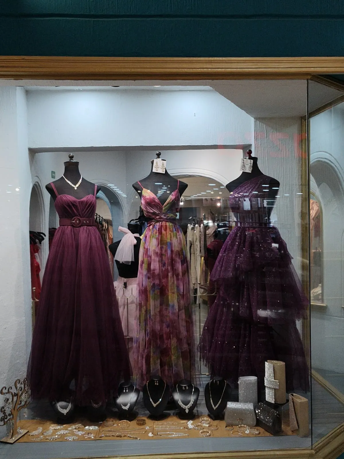Aparador con vestidos ciruela, floral morado y morado de capas, con joyería al frente