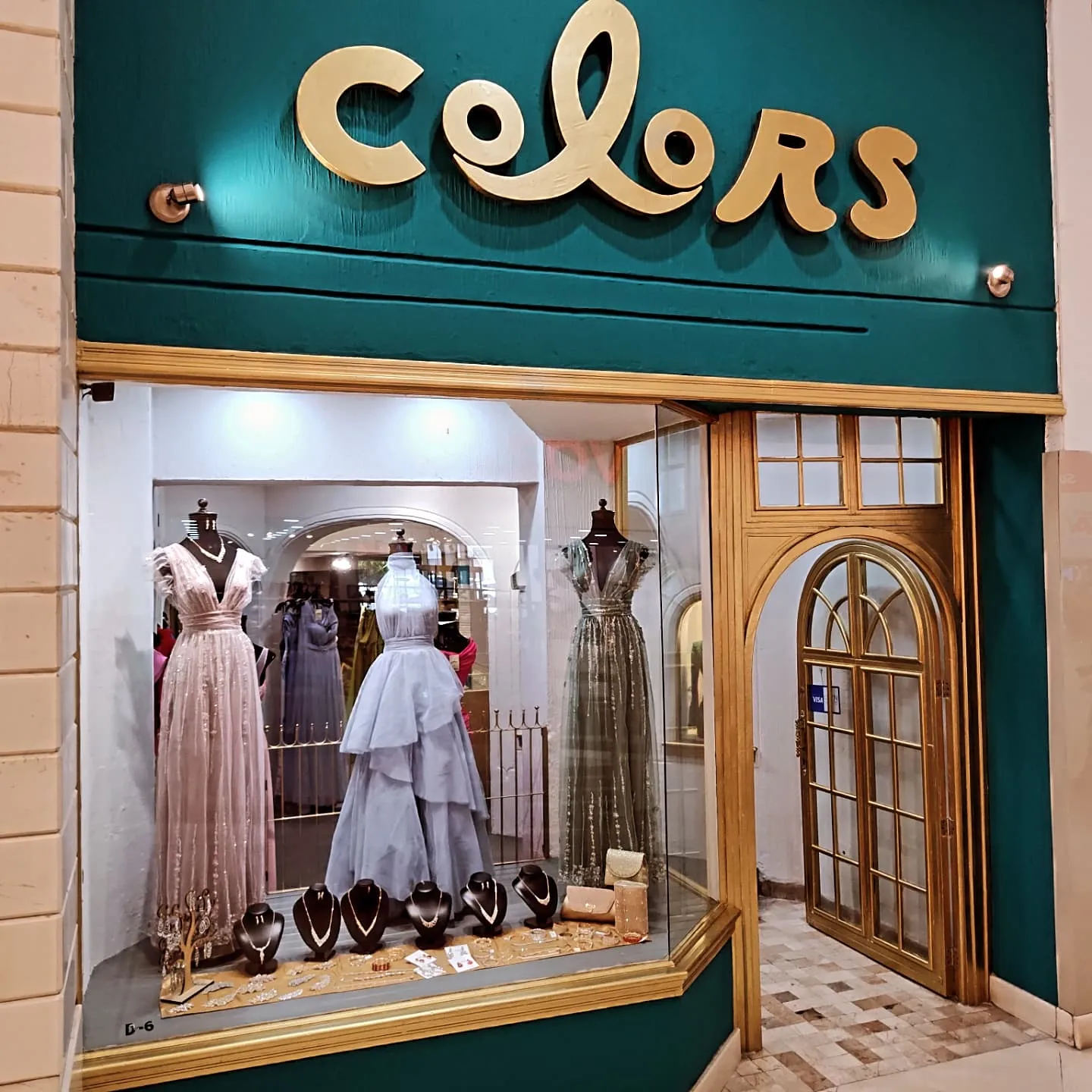 Fachada de Colors en Plaza del Parque: letrero verde con letras doradas y aparador con vestidos y joyería