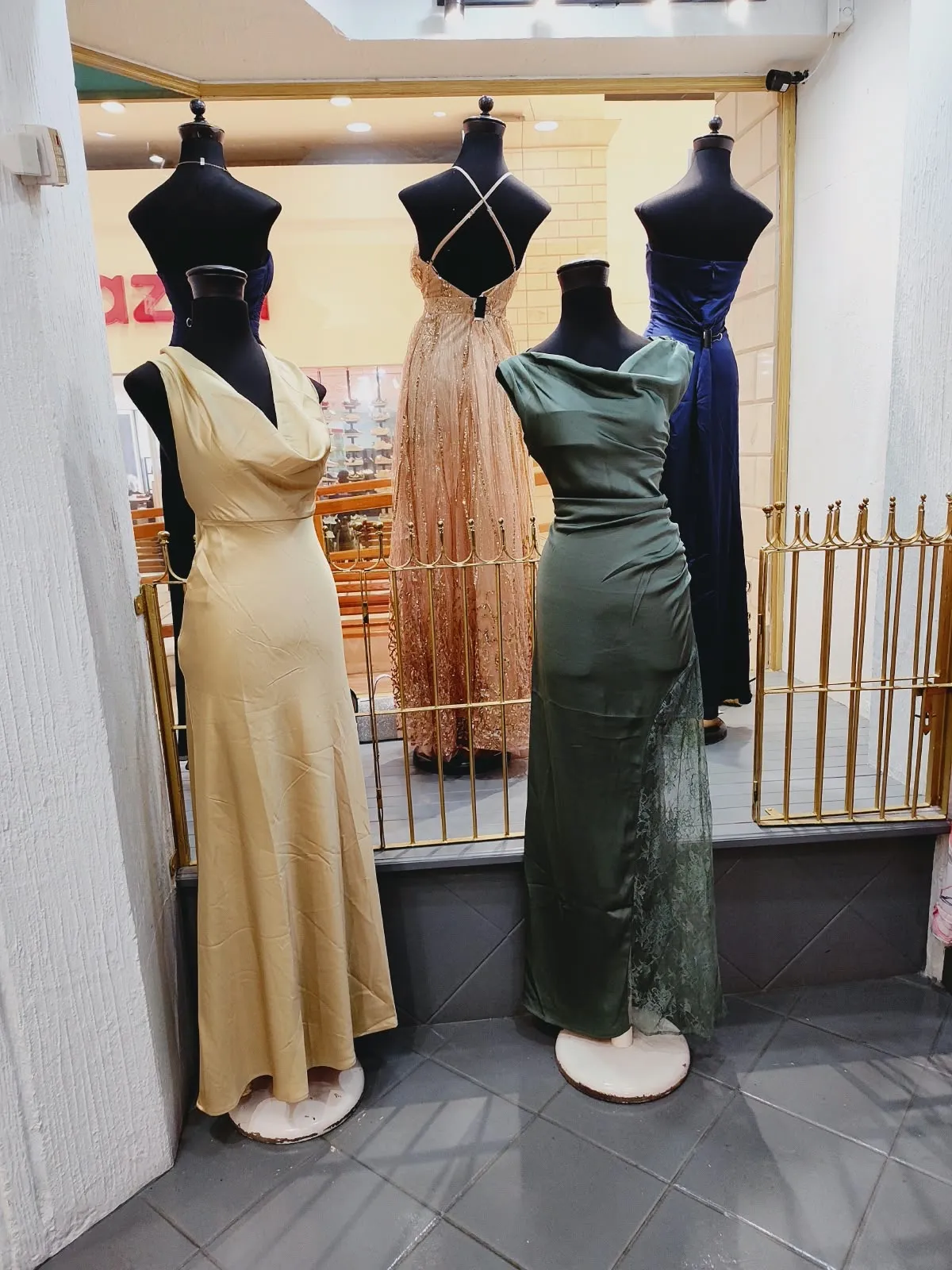 Vestidos largos de satín dorado y verde olivo con cuello caído en la entrada de la tienda
